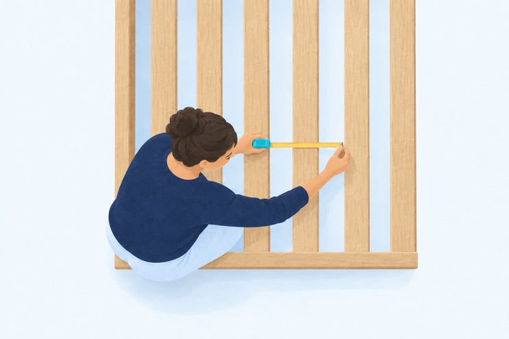 A tape measure held across the gap between two slats on a bed base