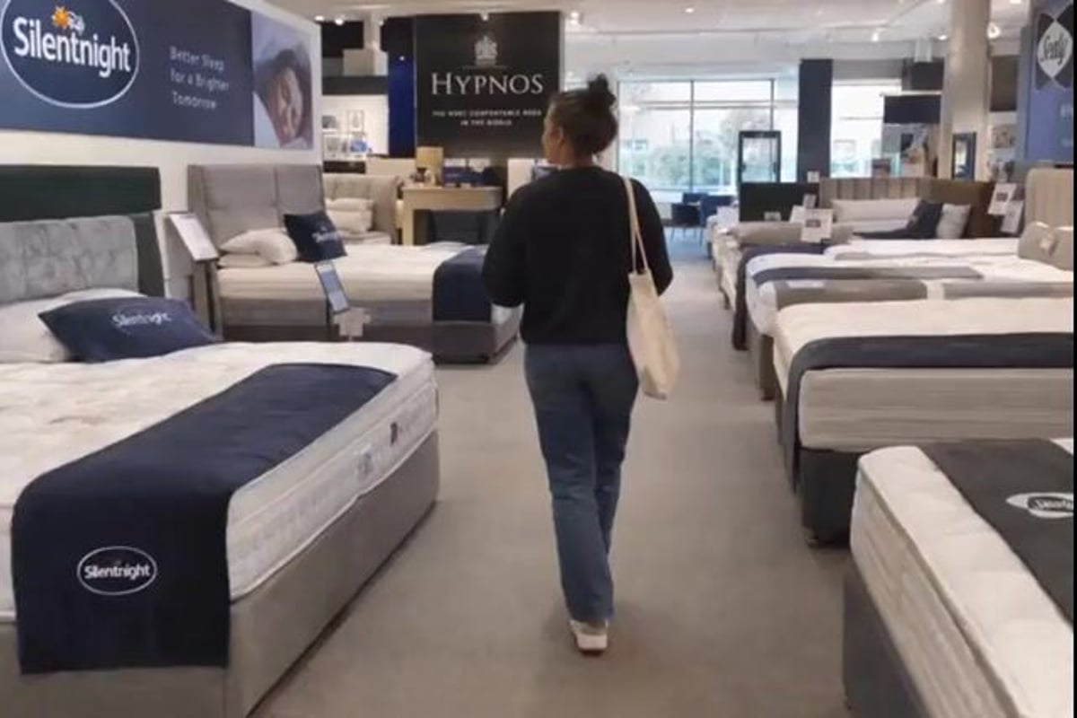 A shopper walking between mattresses in a bed showroom